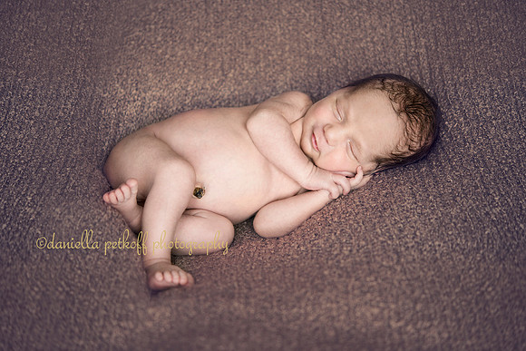 smiling newborn baby boy with umbilical cord