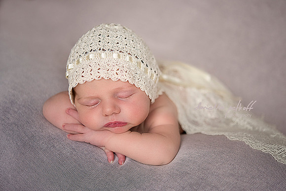 sleeping newborn baby girl covered with lace and with hand crochet hat